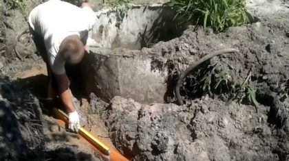 При помощи уровня контролируйте наклон подводящей канализационной трубы, установленной на песчаную подушку в траншее